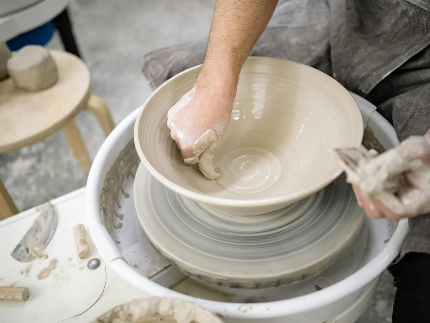 Beginner throwing a serving bowl on the pottery wheel during a class at CLAYA's Denver studio