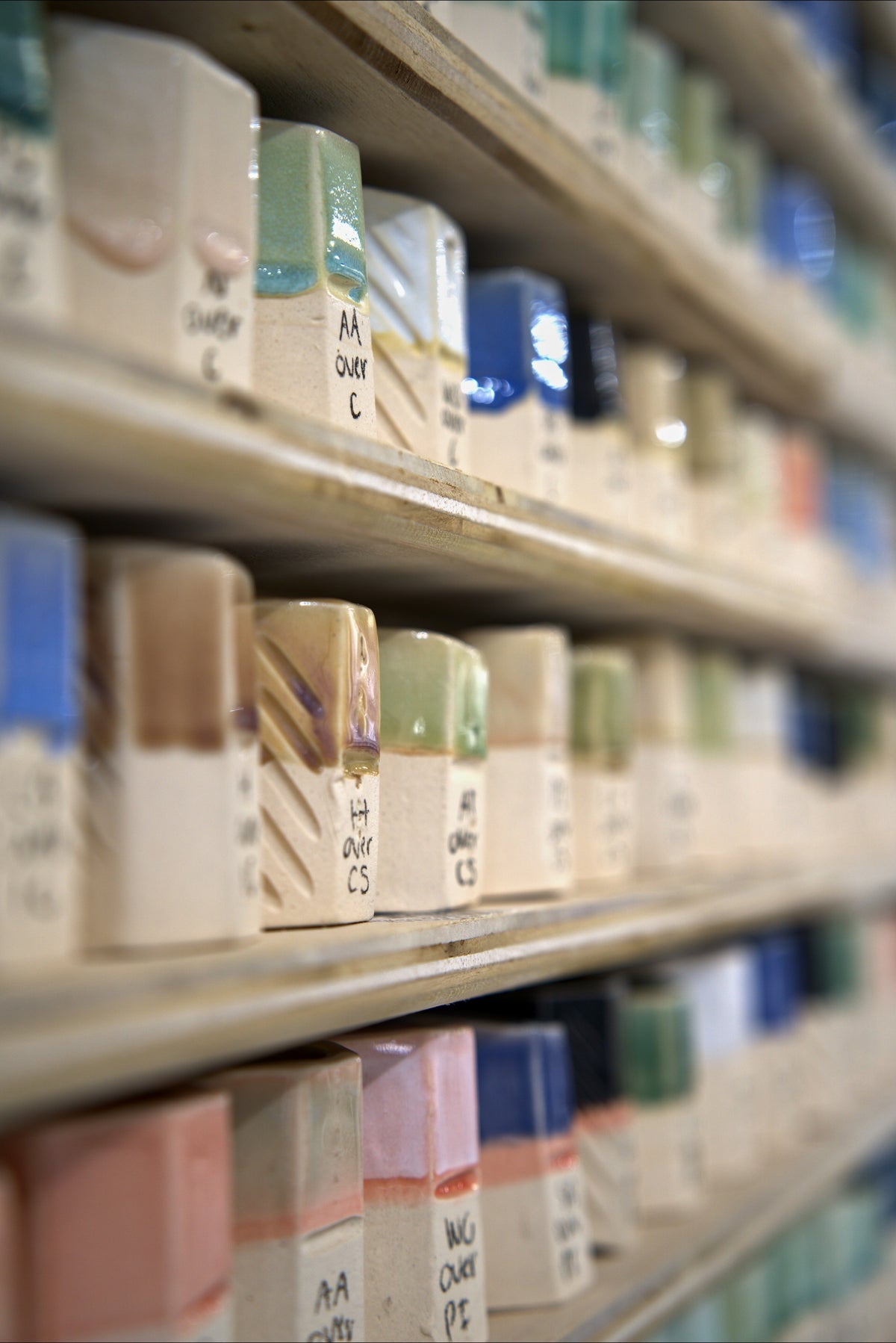 Shelves of glaze test tiles showing studio glazes at Claya, 3440 Walnut Street, Denver