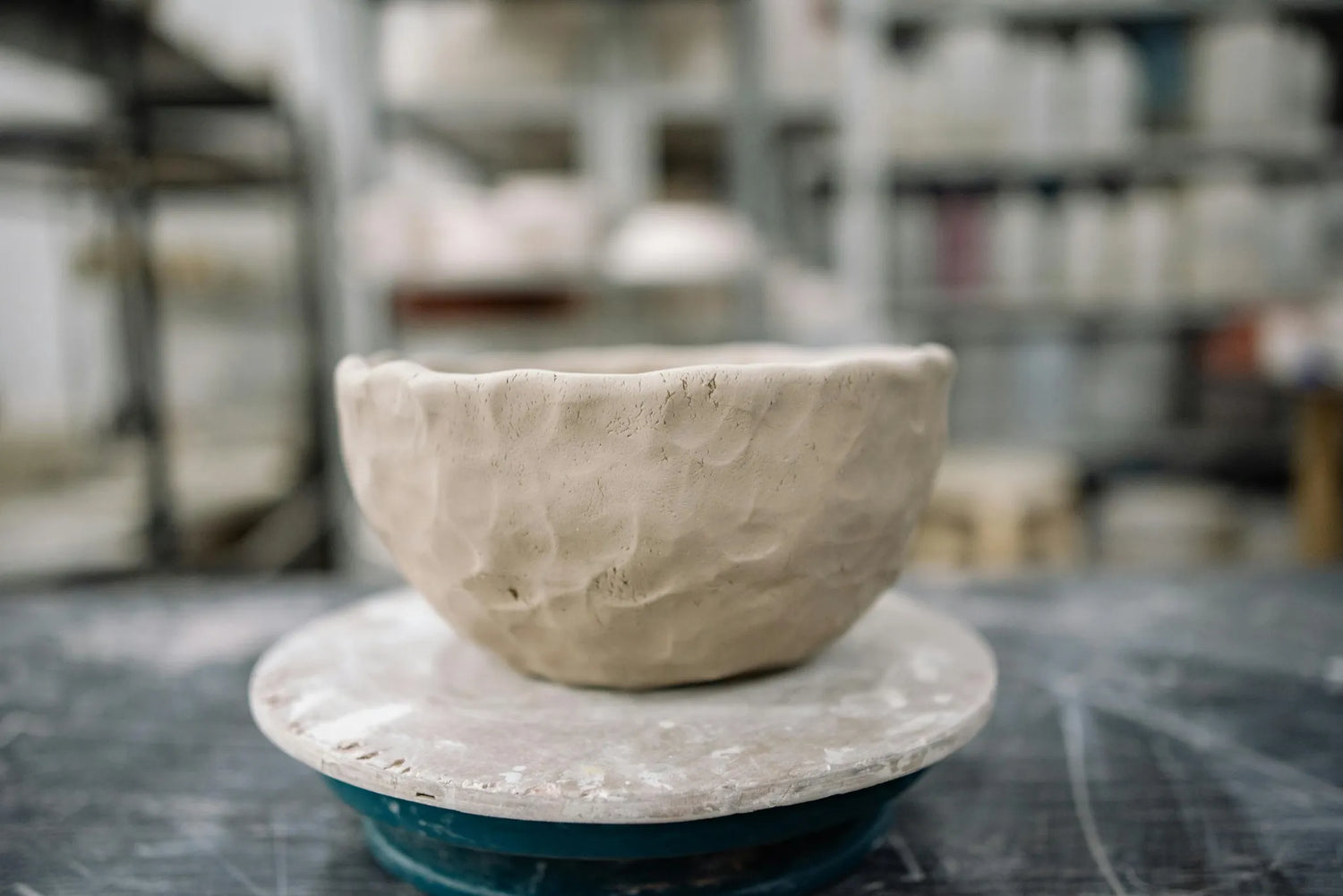 Unfinished ceramic bowl on a wheel in a pottery studio