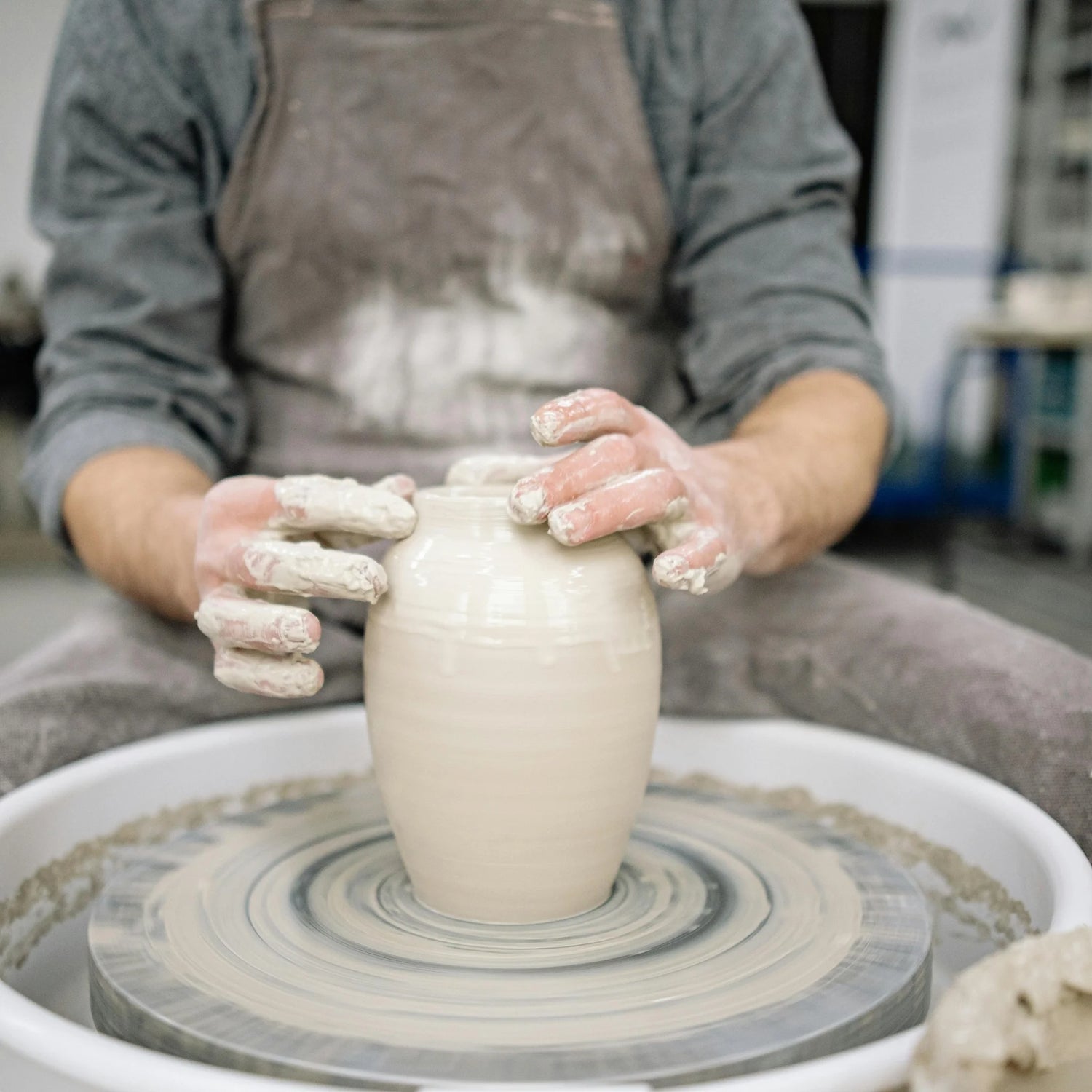 a potter forming a vase at Claya pottery studio during pottery class in Denver