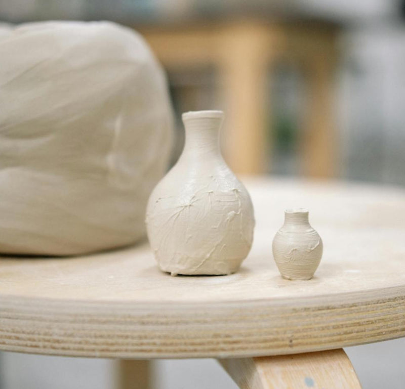 Two ceramic vases on a wooden table with a blurred background