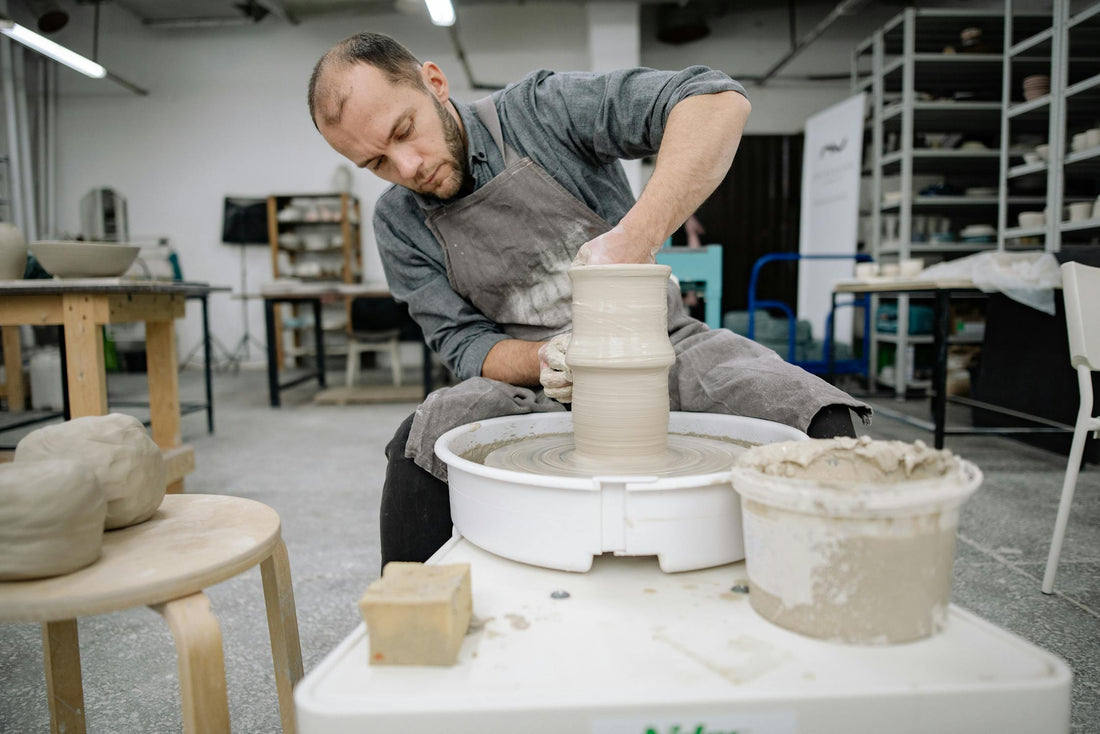 Hands of a potter shaping clay on a pottery wheel