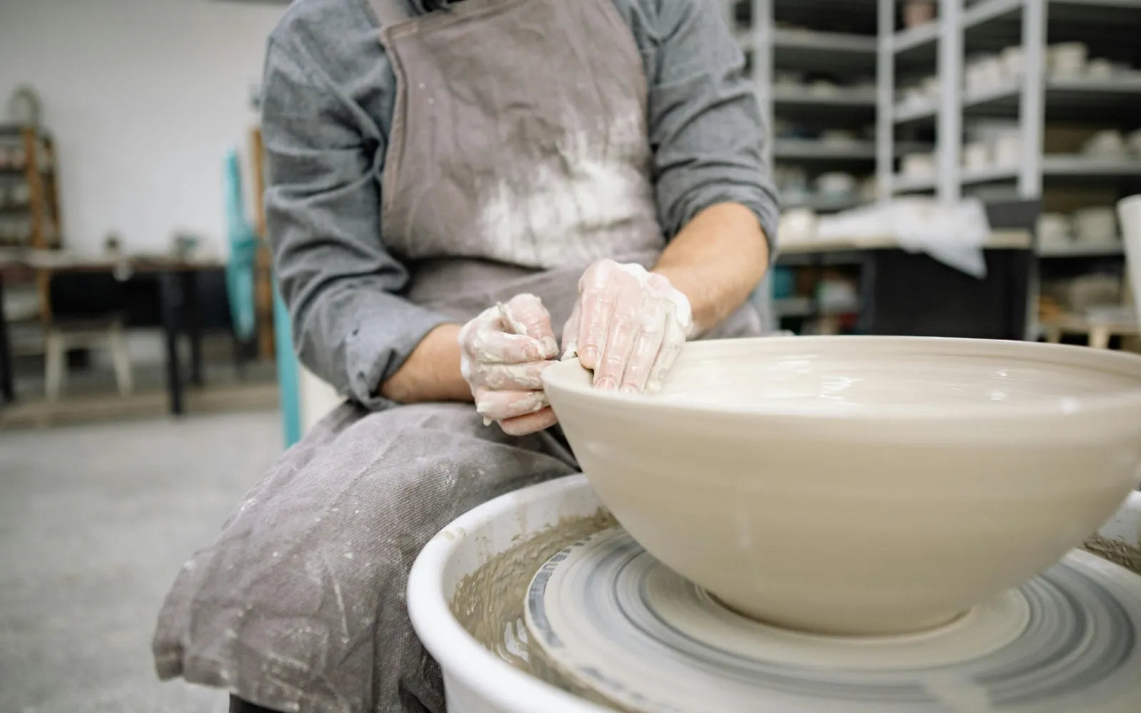 Potter shaping a large serving bowl on the wheel at Claya pottery studio in Denver