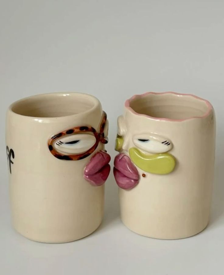 A pair of face mugs with sculpted lips, one wearing glasses
