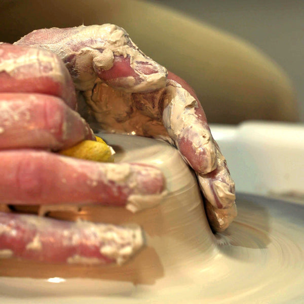 Hands throwing a clay pot on the wheel at Claya pottery studio in RiNo, Denver