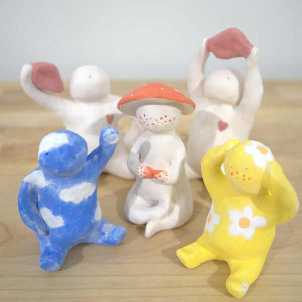 Handbuilt clay figures with sculpted faces, painted in blue, yellow and red underglaze, made at Claya pottery studio in Denver