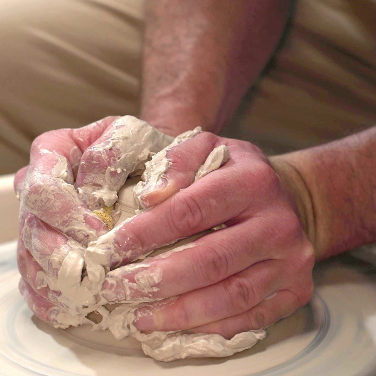 Hands centering clay on a pottery wheel at Claya, 3440 Walnut St, RiNo, Denver