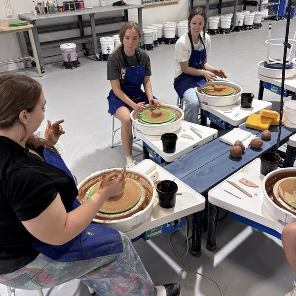Students throwing on pottery wheels in an Intro to Wheel Throwing class at Claya Studios in RiNo, Denver