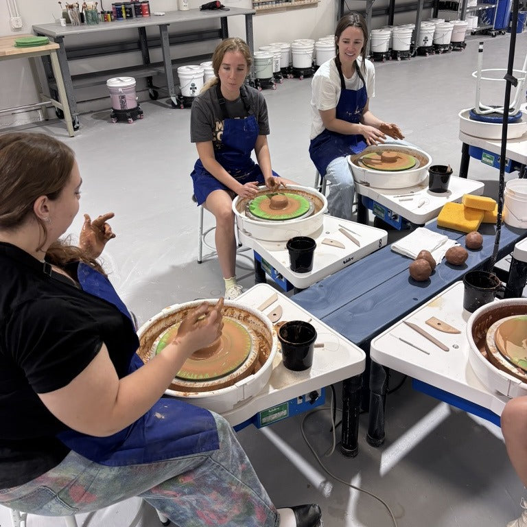 Students throwing on pottery wheels in an Intro to Wheel Throwing class at Claya Studios in RiNo, Denver