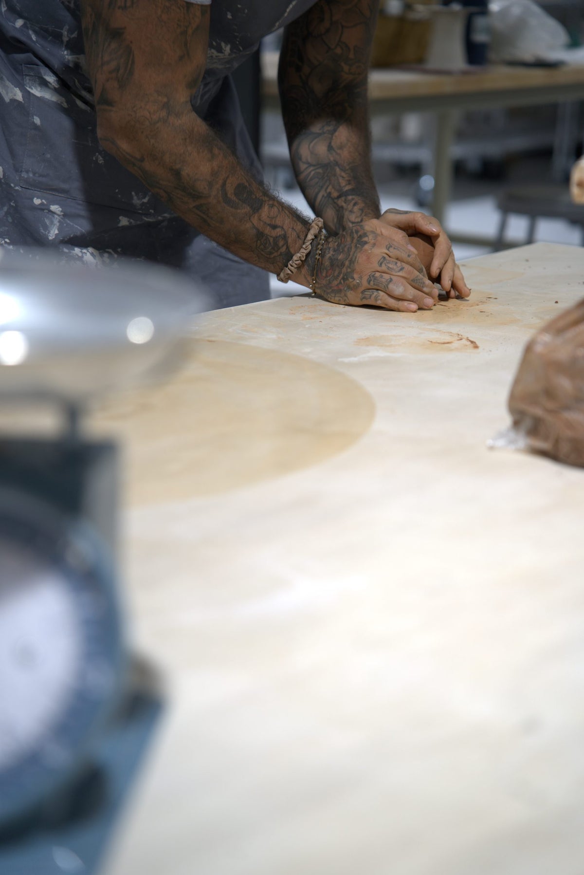Hands wedging clay on a studio worktable before throwing at Claya, RiNo Denver