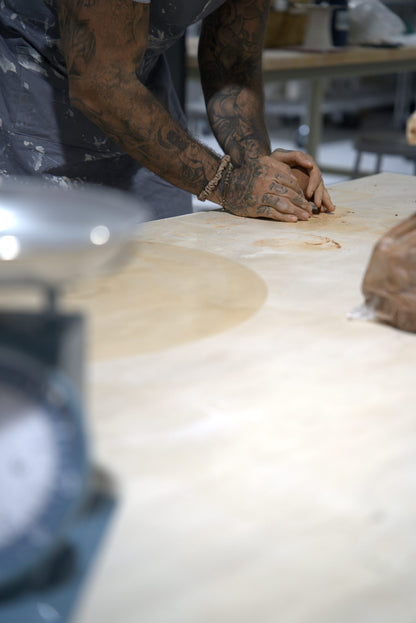 Hands wedging clay on a studio worktable before throwing at Claya, RiNo Denver