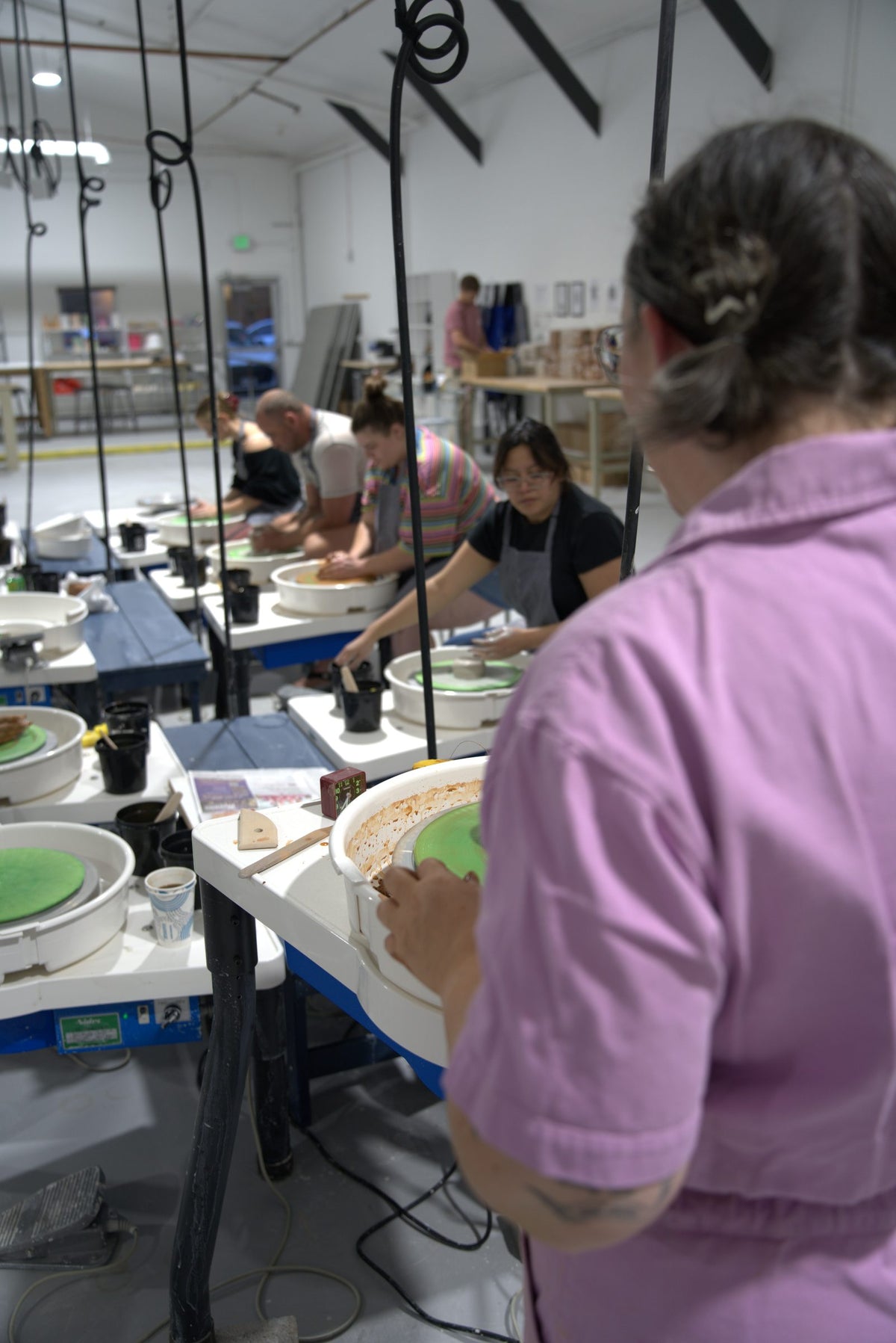 Beginner wheel throwing class at Claya Studios in RiNo, Denver, instructor Caitlin watching over students at their pottery wheels