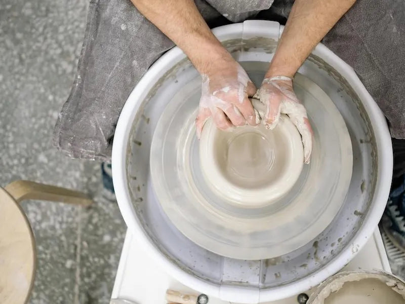 Top-down view of a potter centering clay on the wheel at CLAYA's Denver studio
