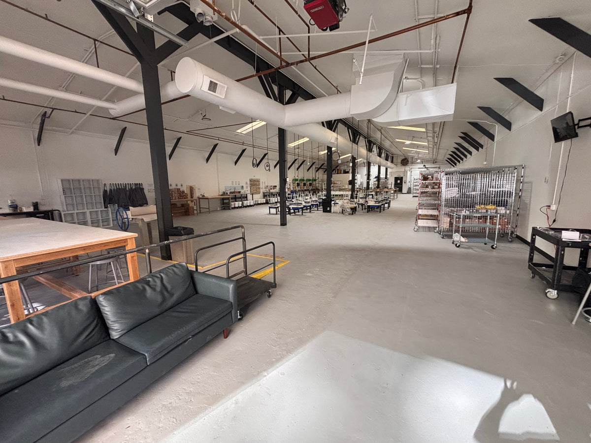 Inside Claya's open pottery studio at 3440 Walnut Street in Denver's RiNo Arts District, with work tables, wheels, and shelving