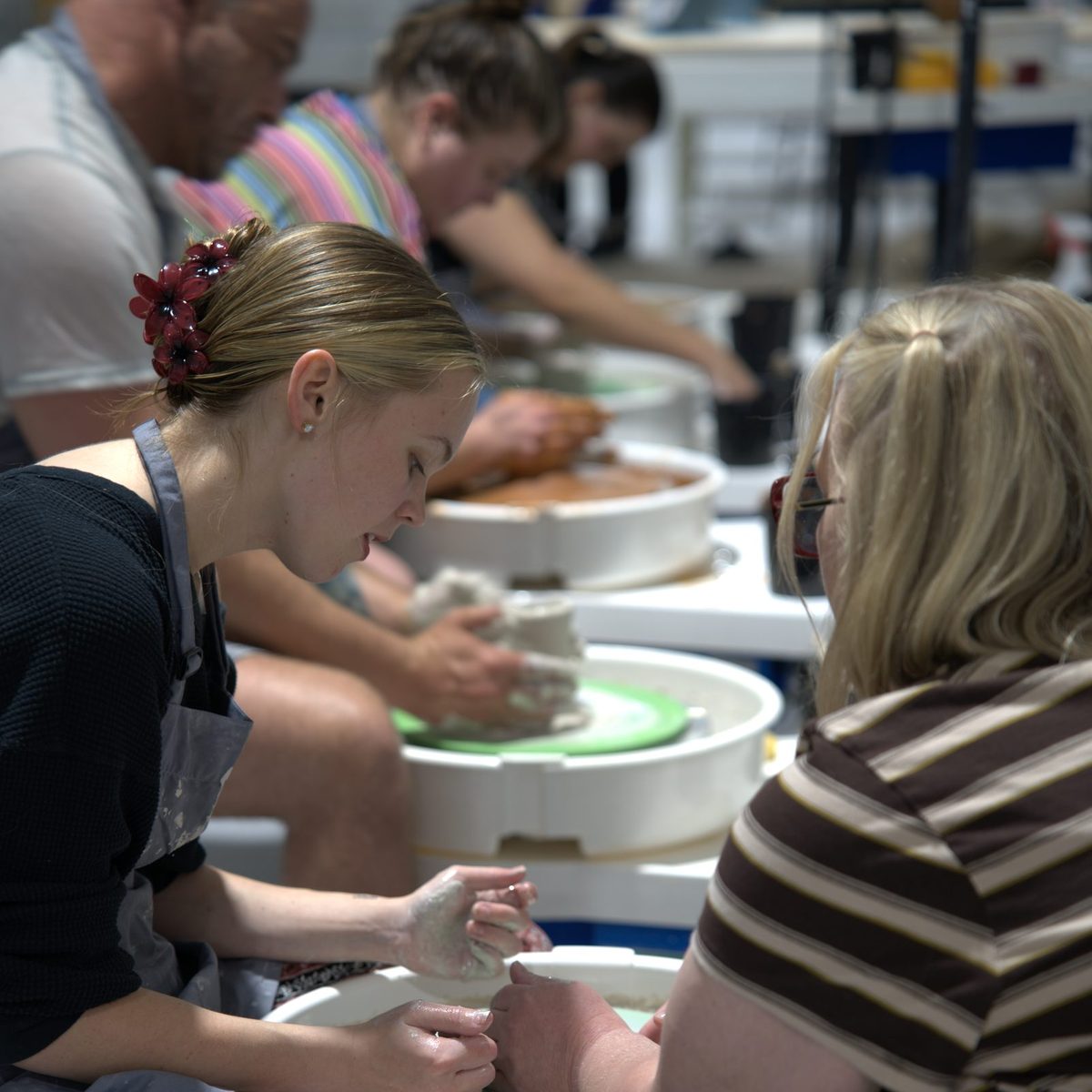 Students throwing side by side on pottery wheels in a class at Claya in RiNo, Denver