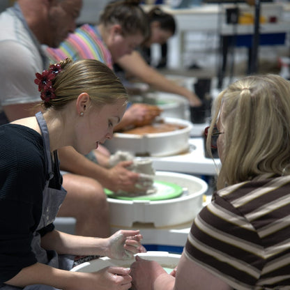 Students throwing side by side on pottery wheels in a class at Claya in RiNo, Denver