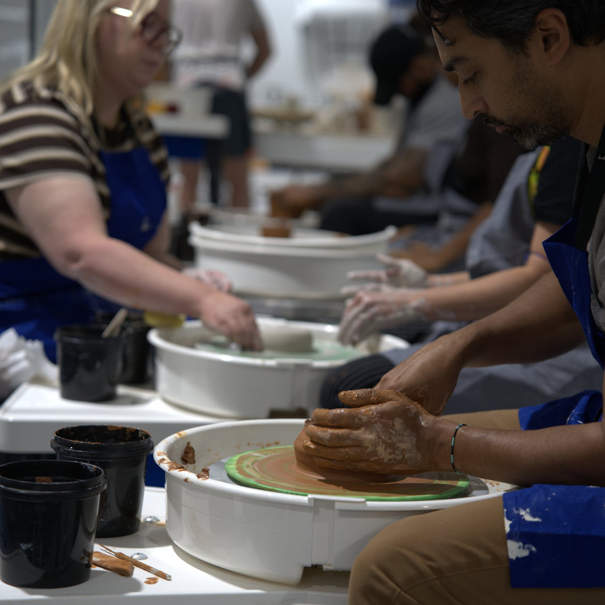 Students centering clay on the pottery wheel in a wheel class at Claya Studios in RiNo, Denver