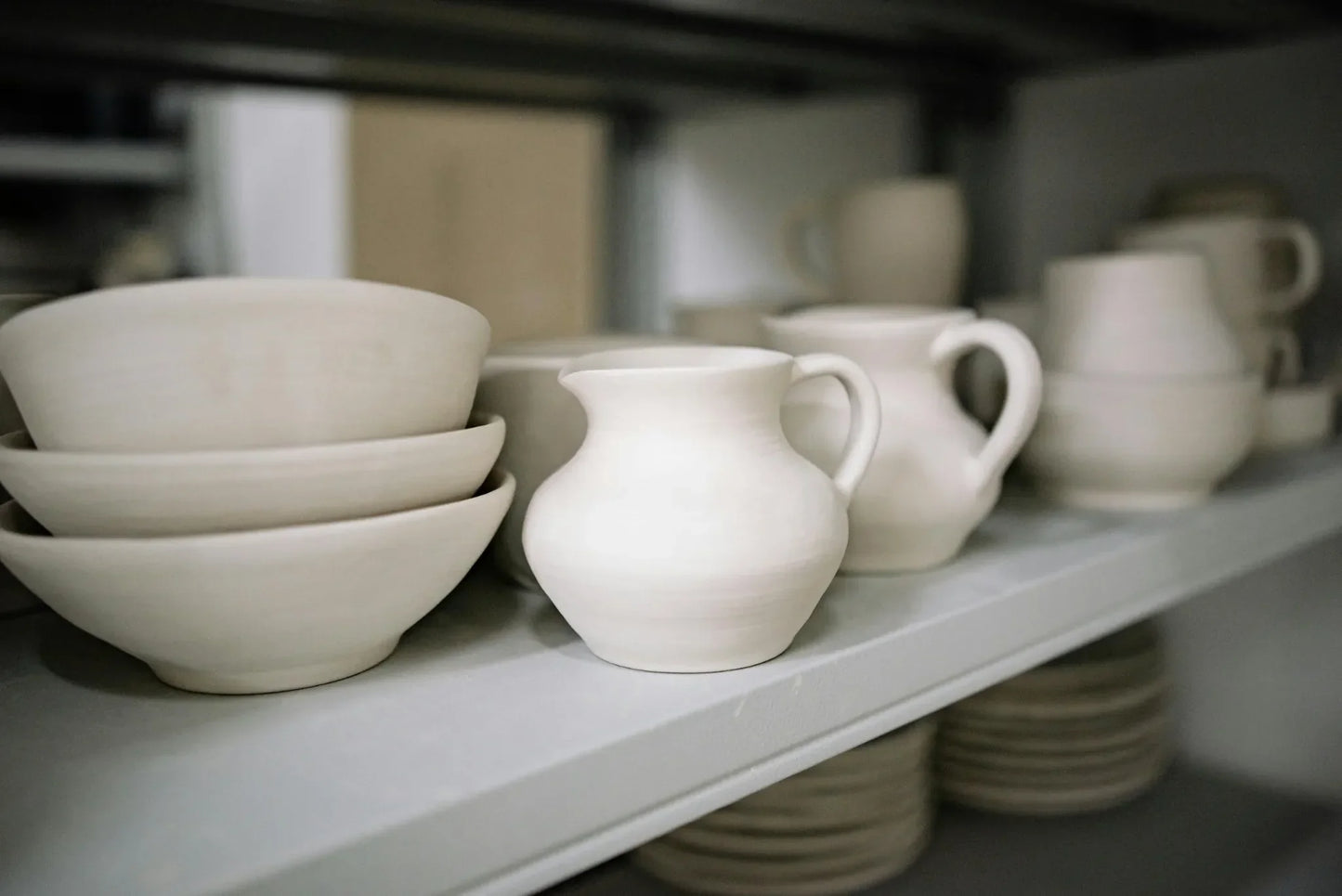 Finished mugs and bowls made by beginner students in Intro to Wheel Throwing class at Claya pottery studio in Denver