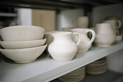 Finished mugs and bowls made by beginner students in Intro to Wheel Throwing class at Claya pottery studio in Denver
