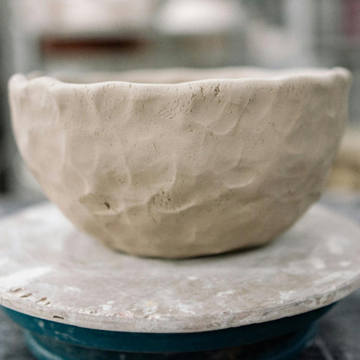 An unfinished ceramic bowl on the wheel, ready for altering, at Claya pottery studio in Denver