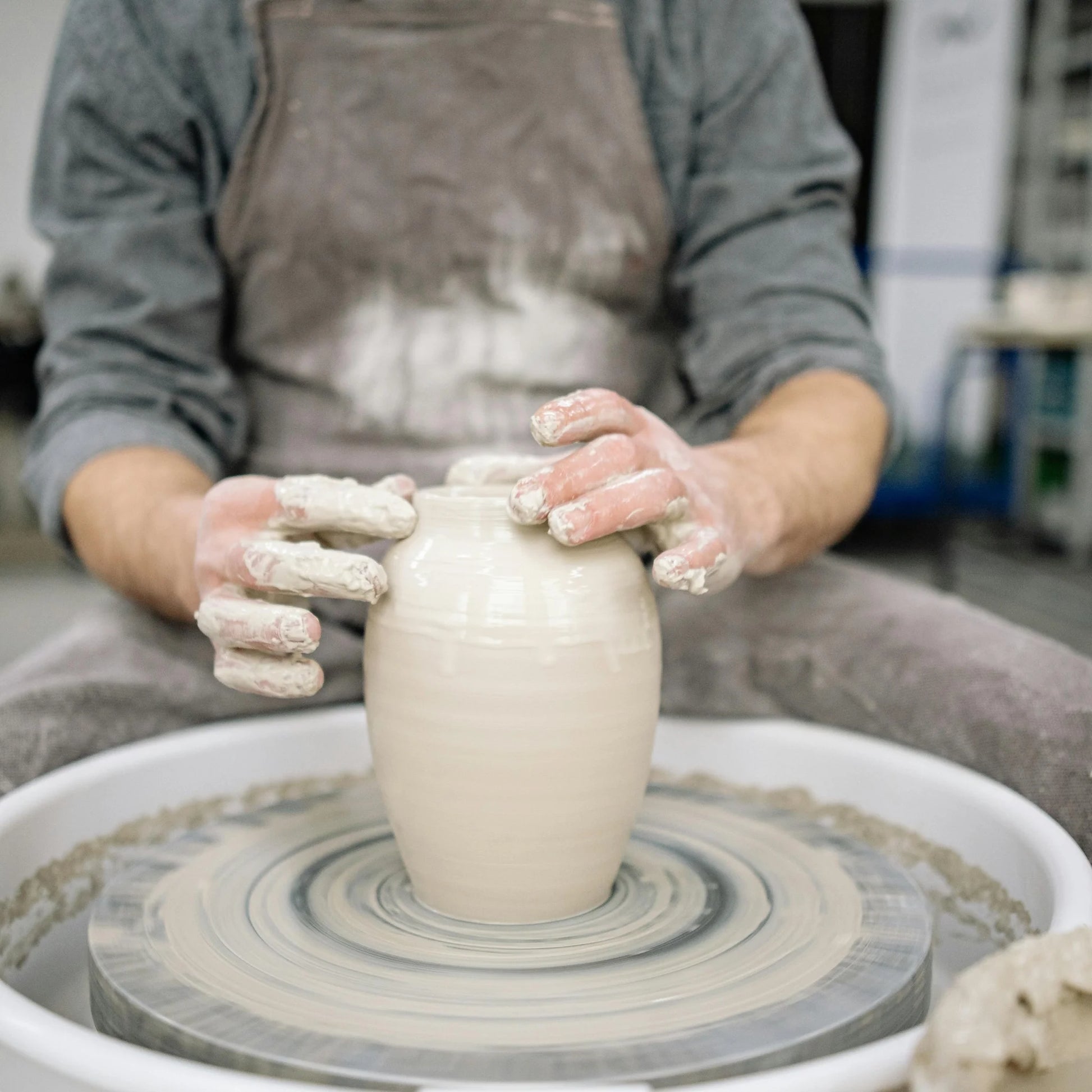 a potter forming a vase at Claya pottery studio during pottery class in Denver
