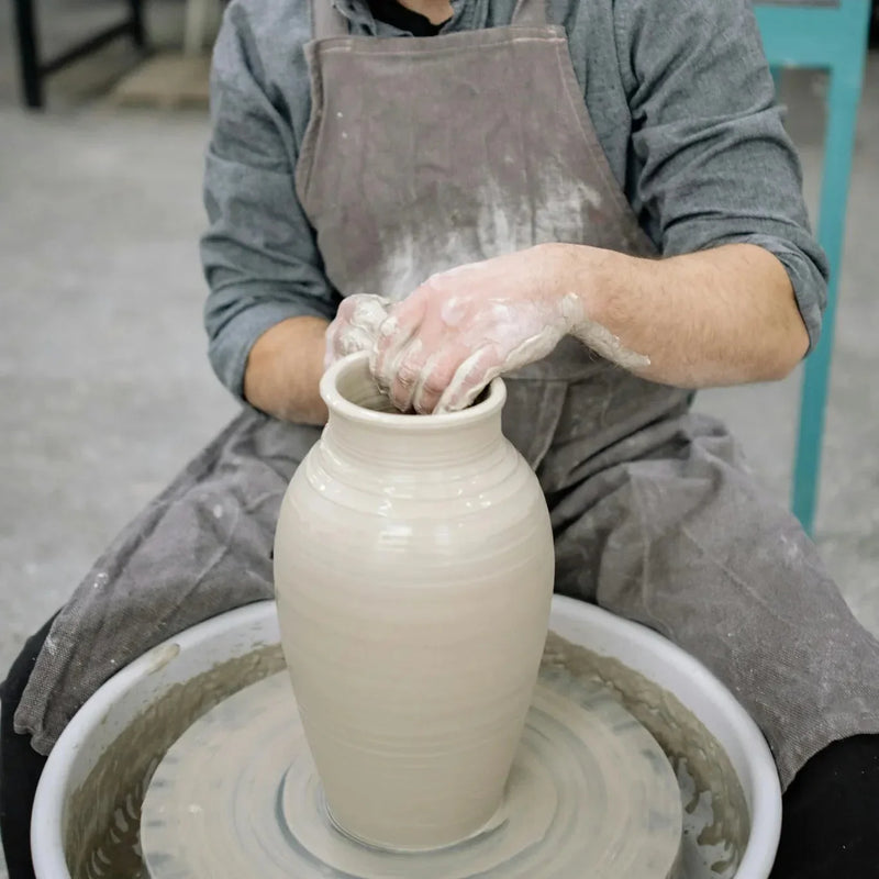 A potter throws a large vase, ready to be altered and reshaped, at Claya pottery studio in Denver