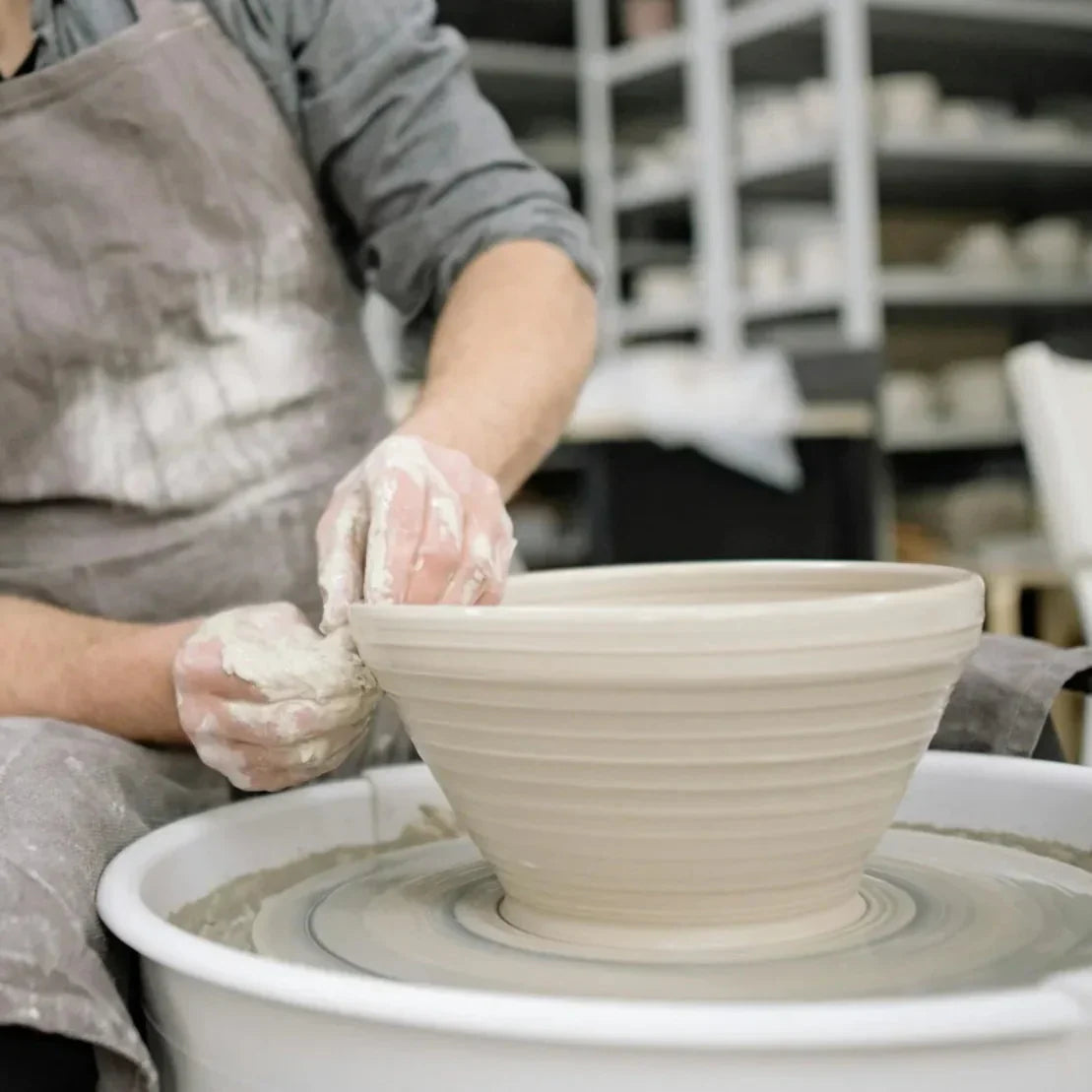 A beginner pulling clay walls on the wheel at Claya