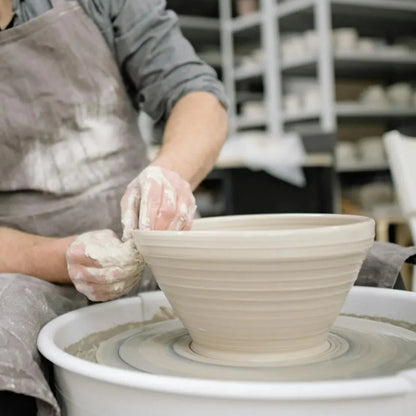 A beginner student pulls clay walls on the pottery wheel during Intro to Wheel Throwing class at Claya in Denver