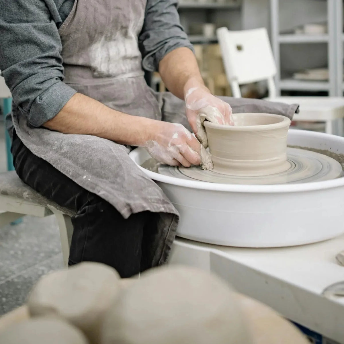 Potter shaping clay on the pottery wheel at a Denver ceramics studio