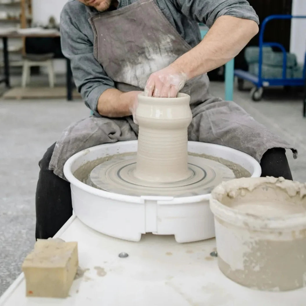 A member throwing pottery on the wheel at Claya in Denver